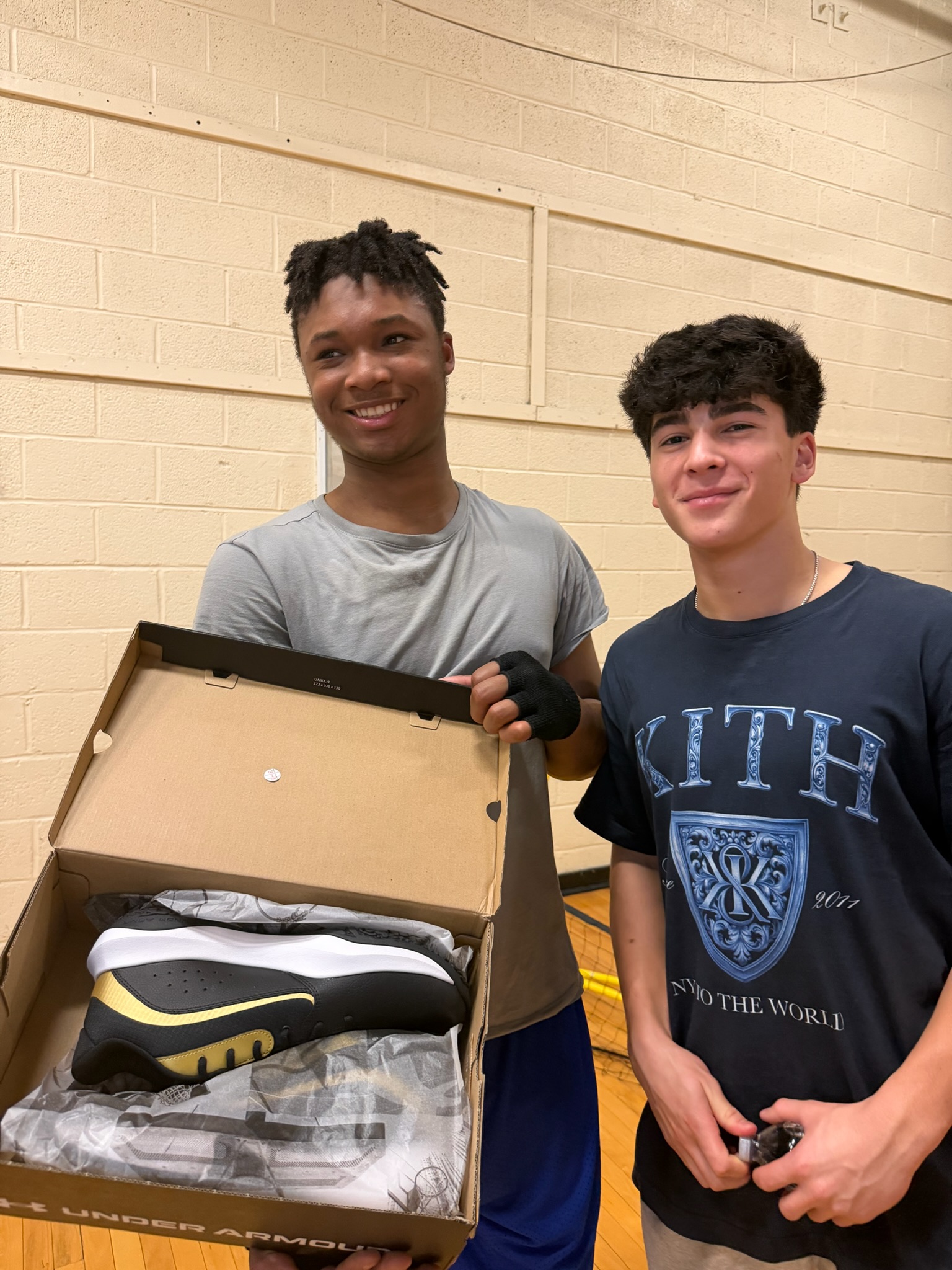 Two participants holding a box of the donated basketball sneakers
